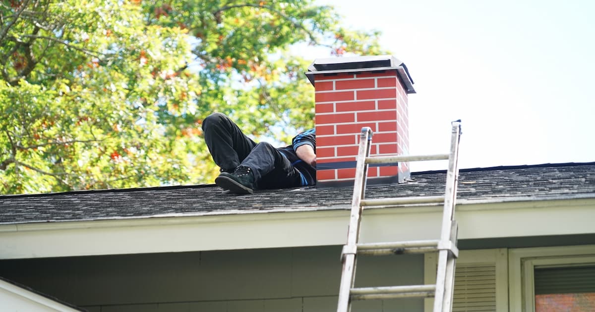 man die werkt op een dak met een schoorsteen